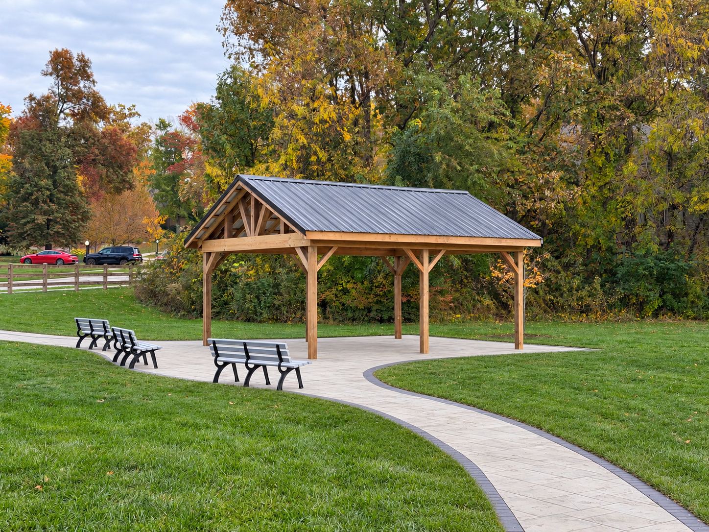 Completed timber pavilion with metal roof beside the paved walkway and benches